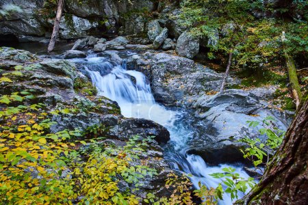 Téléchargez les photos : Image du feuillage jaune et des roches entourant la rivière avec des chutes d'eau en cascade à New York - en image libre de droit