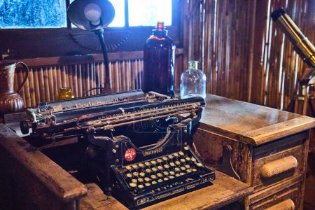 Téléchargez les photos : Image de la scène de nature morte de la vieille machine à écrire sur un vieux bureau en bois avec des objets anciens comme des bouteilles autour - en image libre de droit