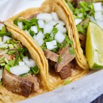 Image of Lengua chow beef tongue 3 street tacos Mexican with cilantro, lime wedge, and onions