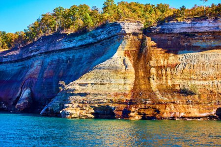 Photo for Image of Forest above Pictured Rocks cliff with archway through stone and calm lake water - Royalty Free Image