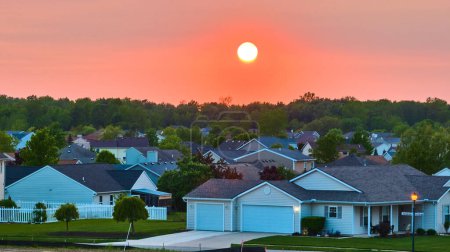 Téléchargez les photos : Image du coucher de soleil rouge et orange sur les maisons de banlieue dans la forêt voisine skyline aérienne - en image libre de droit