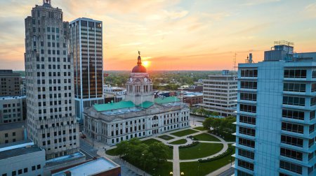 Téléchargez les photos : Image du soleil doré culminant sur l'horizon derrière le palais de justice dans l'antenne du centre-ville de Fort Wayne - en image libre de droit