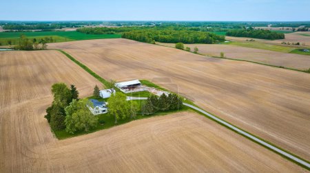 Image of Aerial clean farmhouse landscape property aerial with green runoff ditches, paved road, empty fields