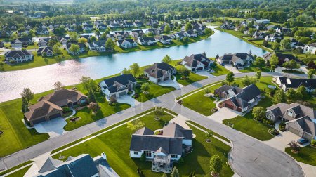 Image of Summertime in expensive neighborhood with landscaped yards next to pond aerial