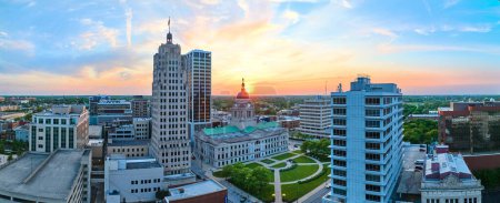 Téléchargez les photos : Image du lever du soleil du matin doré du centre-ville de Fort Wayne dans un ciel bleu brillant - en image libre de droit