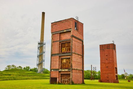Foto de Imagen de restos abandonados de antiguos edificios de elevadores de carga de fábrica de vidrio y torre de vigilancia distante - Imagen libre de derechos
