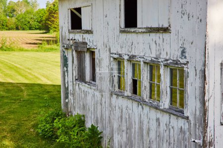 Photo for Image of Side of abandoned white country home with chipped paint and busted windows - Royalty Free Image