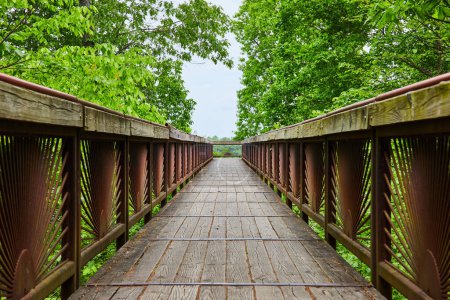 Photo for Image of Bridge with rusty rising sun pattern on railing with worn wooden plank path leading to overlook - Royalty Free Image