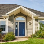 Image of Gray siding house blue front door, arch entryway, slate gray checkered roof landscaping asset