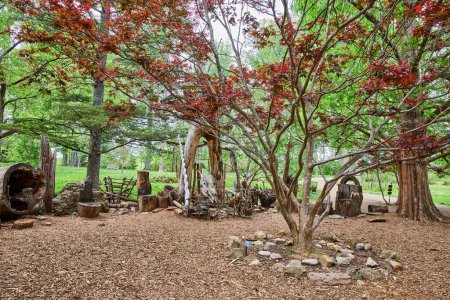 Photo for Image of Campsite with maroon leaves on tree and circle of stones around base a dragon skull and unicorn horn - Royalty Free Image