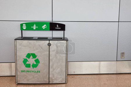 Téléchargez les photos : Image du réceptacle de recyclage générique avec section poubelle contre une longue paroi grise avec slogan Ind Recycles - en image libre de droit