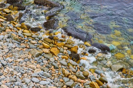 Photo for Image of Peaceful water lapping at stones against a rocky shore in zen background asset - Royalty Free Image