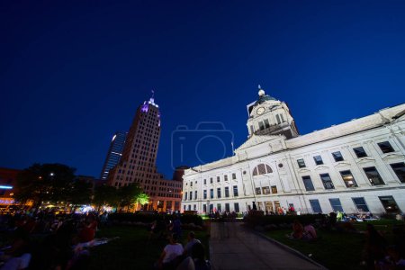 Téléchargez les photos : Image de la foule sur la pelouse du palais de justice du comté d'Allen la nuit avec des bâtiments éclairés - en image libre de droit