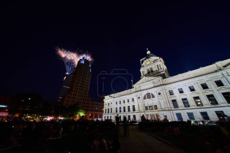 Téléchargez les photos : Image de feux d'artifice la nuit derrière la tour Lincoln avec des gens entassés pelouse du palais de justice au centre-ville de Fort Wayne - en image libre de droit