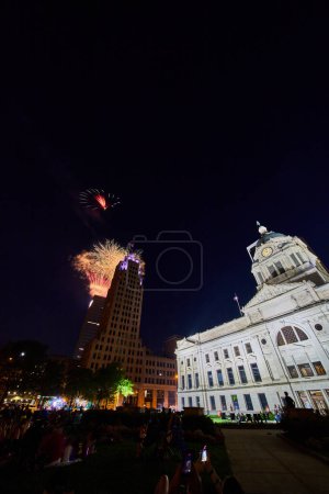 Téléchargez les photos : Image de feux d'artifice au centre-ville de Fort Wayne avec le palais de justice et la foule de gens qui regardent - en image libre de droit