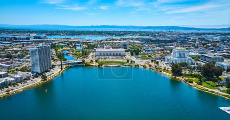 Photo for Image of Lone sailboat on Lake Merritt with apartment building and courthouse with convention center aerial - Royalty Free Image
