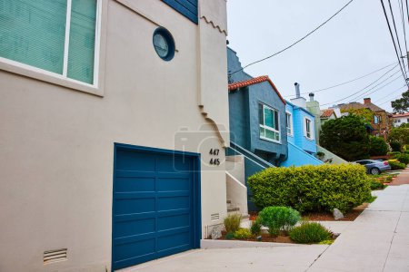 Téléchargez les photos : Image Maison blanche avec porte de garage bleu TARDIS dans le quartier californien avec fils de transit au-dessus - en image libre de droit
