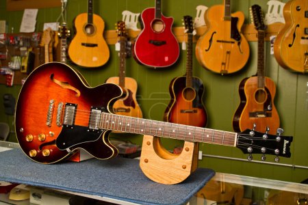 Foto de Exquisita artesanía exhibida en una diversa selección de guitarras en una tienda de música en Fort Wayne, Indiana. Una impresionante explosión de sol semi-hueca guitarra eléctrica toma el centro del escenario, rodeado por una matriz - Imagen libre de derechos