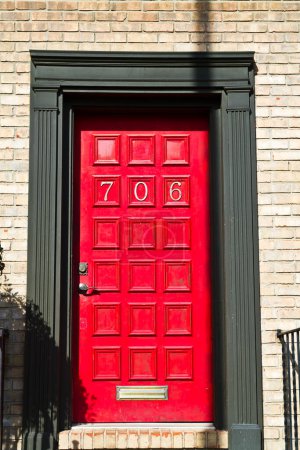 Foto de Casa número 706 en la puerta roja vibrante con una fachada de pared de ladrillo urbano - Una entrada de bienvenida en Evansville, Indiana - Imagen libre de derechos