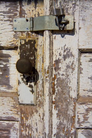 Téléchargez les photos : Gros plan de Rusty Padlock sur une porte en bois vieillie à la centrale électrique abandonnée d'Auburn, en Indiana - Étude sur la texture, la pourriture et le temps. Peinture blanche écaillée sur porte en bois. - en image libre de droit