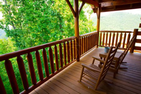 Tranquil forest view from a rustic wooden porch in Gatlinburg, Tennessee. Enjoy peaceful moments in wooden rocking chairs amidst lush greenery.