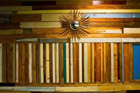 Téléchargez les photos : Décor mural d'inspiration vintage avec planches de bois récupérées en différentes couleurs et textures, complété par un miroir solaire rétro. Parfait pour le design d'intérieur respectueux de l'environnement et le décor artistique à la maison - en image libre de droit