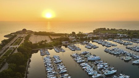 Foto de Imagen de Barcos en muelles en Burnham Harbor con el sol dorado saliendo del lago Michigan, Chicago, IL - Imagen libre de derechos