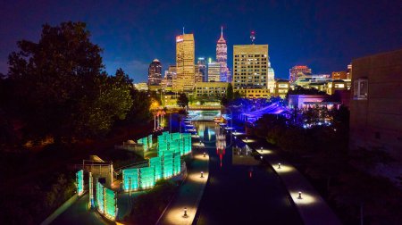 Illuminated Indianapolis nightscape featuring vibrant city park, futuristic canal pathway, and diverse skyline, captured from an aerial perspective by a DJI Mavic 3 drone