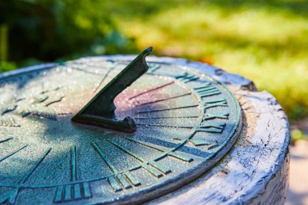 Photo for Sundial in Muncie conservatory garden, Indiana, displaying time amidst dappled sunlight and morning dew, hinting at antiquity and the tranquil passing of the day. - Royalty Free Image