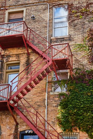 Photo for 2023 view of a rustic brick building with a red fire escape and climbing ivy in Downtown Elkhart, Indiana showing urban resilience over time. - Royalty Free Image
