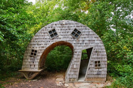 Photo for Surreal, arch-shaped wooden house with topsy-turvy design amidst lush greenery at an art center in Indianapolis, Indiana, 2023 - Royalty Free Image