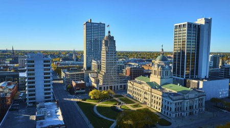 Foto de Vista aérea soleada de Fort Wayne, Indiana, que muestra la diversidad arquitectónica con un palacio de justicia histórico en medio de rascacielos modernos, en medio de calles tranquilas de otoño. - Imagen libre de derechos