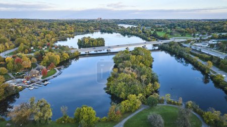 Foto de Atardecer sobre la tranquila ribera del río Michigan, vista aérea de árboles y puentes otoñales - Imagen libre de derechos