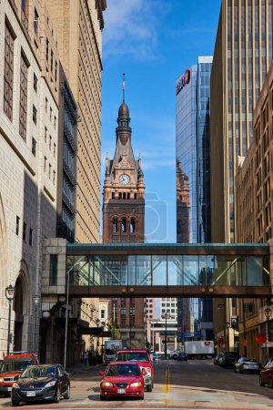 Foto de Torre histórica del reloj en medio de la arquitectura moderna bajo un cielo despejado, que simboliza Milwaukees mezcla de viejo y nuevo, conectado por una carretera concurrida y un skywalk. - Imagen libre de derechos