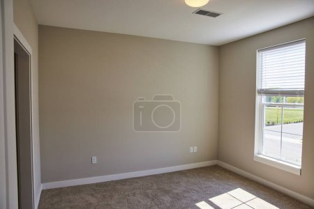 Photo for Empty, modern interior of a Fort Wayne home in Indiana, filled with natural light, featuring beige walls and brown carpet, ready for personalized decoration. - Royalty Free Image