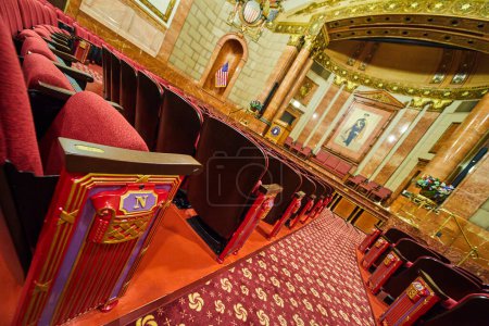 Foto de Opulento interior del teatro War Memorial Museum en Indianápolis, Indiana, con lujosos asientos de terciopelo rojo y un gran escenario bajo una cálida iluminación ambiental. - Imagen libre de derechos