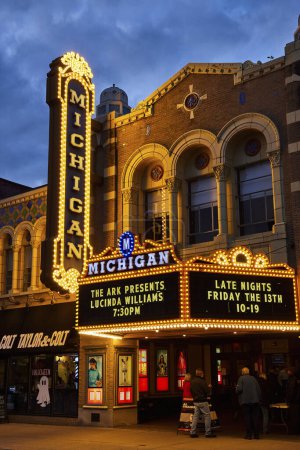 Foto de Crepúsculo multitud se reúne en el iluminado Teatro Michigan en el centro de Ann Arbor, mostrando la arquitectura histórica y la vibrante vida nocturna. - Imagen libre de derechos
