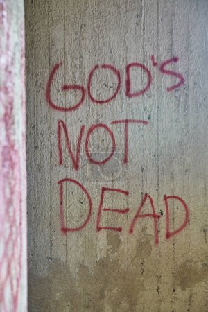 Photo for Gritty urban graffiti stating GODS NOT DEAD on a concrete wall at the historic Columbus Grain Elevator, Ohio. - Royalty Free Image
