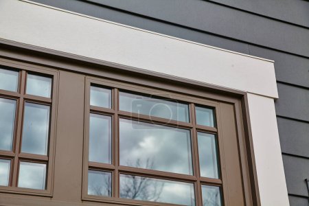 Téléchargez les photos : Gros plan d'une fenêtre résidentielle moderne sur un mur gris foncé reflétant un ciel couvert, mettant en valeur l'architecture contemporaine dans l'Indiana, 2015 - en image libre de droit