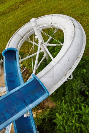Photo for High-angle view of an abandoned white and blue water slide overtaken by lush greenery in Fun Spot, Angola, Indiana, captured in 2015 on an overcast day - Royalty Free Image