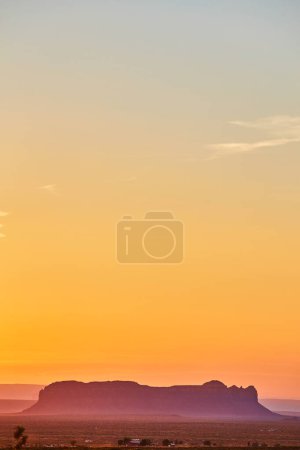 Photo for Golden hour paints a tranquil scene over the silhouette of an iconic mesa in Arizonas Monument Valley, Sedona, 2016 - Royalty Free Image
