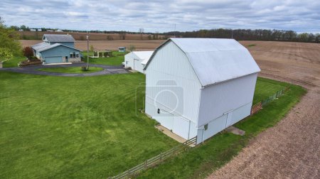 Foto de Vista aérea de la serena granja de Indiana con granero blanco tradicional, casa azul y extensos campos, capturado por DJI Phantom 4 drone en 2017 - Imagen libre de derechos