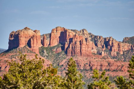 Sedonas vibrantes formaciones rocosas rojas bajo cielo azul claro, enmarcadas por follaje siempreverde, Arizona 2016