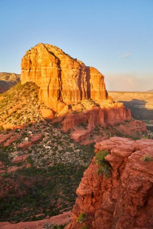 Photo for Golden hour illuminates the striking strata of Bell Rock in Sedona, Arizona, contrasting the red rock formation with surrounding greenery, 2016 - Royalty Free Image