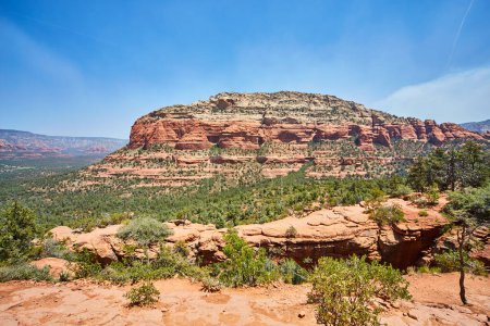 Breathtaking view of red sandstone cliffs and desert vegetation under clear blue sky in Sedona, Arizona, showcasing the timeless beauty of the American Southwest.