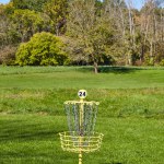 Sunny Disc Golf Course at France Park Falls, Indiana, 2016 - A serene, mid-morning view of hole 24s vibrant yellow basket on a well-manicured lawn, framed by early autumn trees.