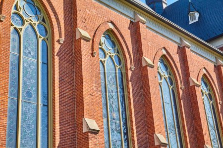 Photo for Gothic-inspired St. Peters Catholic Church in Fort Wayne, Indiana, highlighted by gleaming stained glass and red brickwork under a clear sky - Royalty Free Image