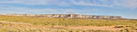 Foto de Vista panorámica de majestuosas formaciones de mesetas bajo un cielo azul claro en Sedona, Arizona, con escasa vegetación desértica y una valla fronteriza - Imagen libre de derechos
