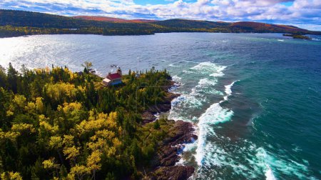 Breathtaking aerial view of a secluded lighthouse on rugged coastline with autumn forest, Copper Harbor Lighthouse, Michigan, captured by DJI Phantom 4 drone