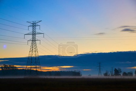 Sonnenaufgang beleuchtet hoch aufragende Stromleitungen über nebligen Feldern in Michigan, Herbst 2017: Ein Zeugnis für Natur und menschliche Innovation